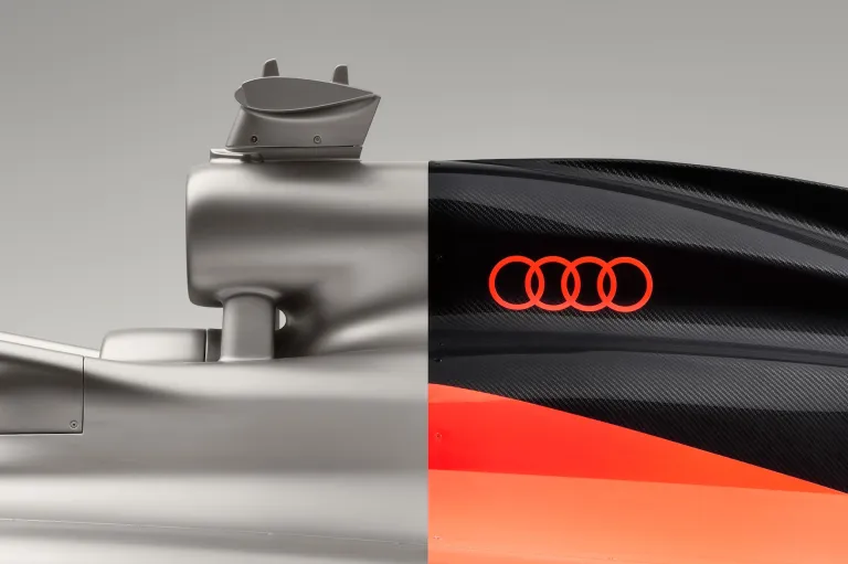 The Audi R26 Formula 1 car uses precise color blocking and exposed carbon fiber to complement its aerodynamic architecture.